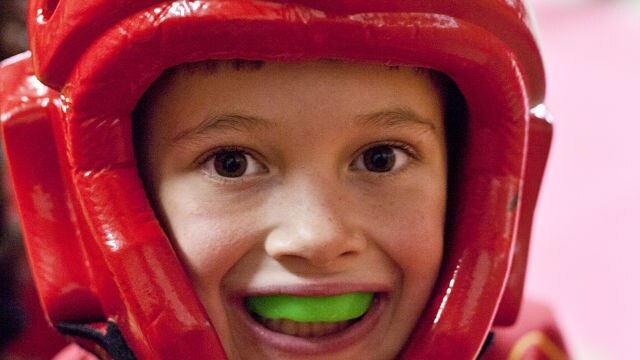 Niño con casco deportivo rojo y protector bucal