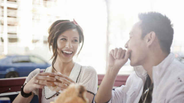 Hombre y mujer almorzando y riendo