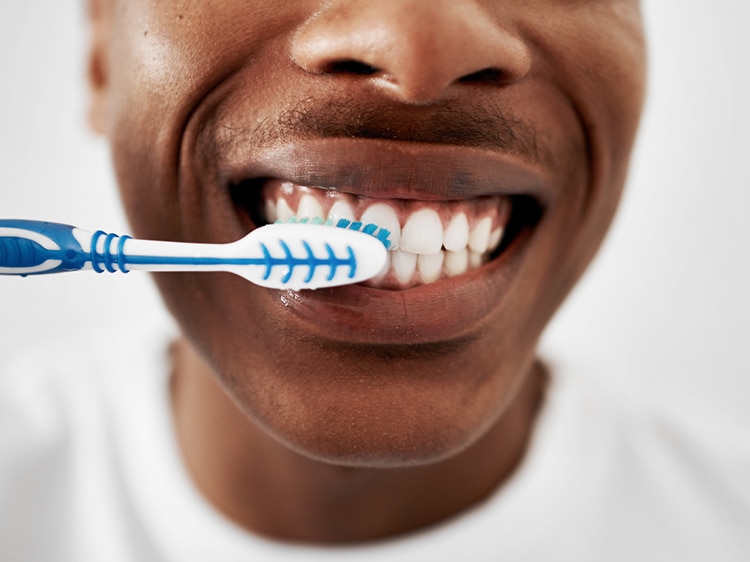 man brushing teeth with colgate toothbrush