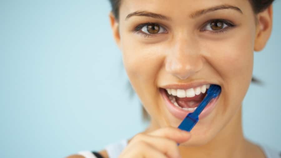 Mujer joven cepillándose los dientes