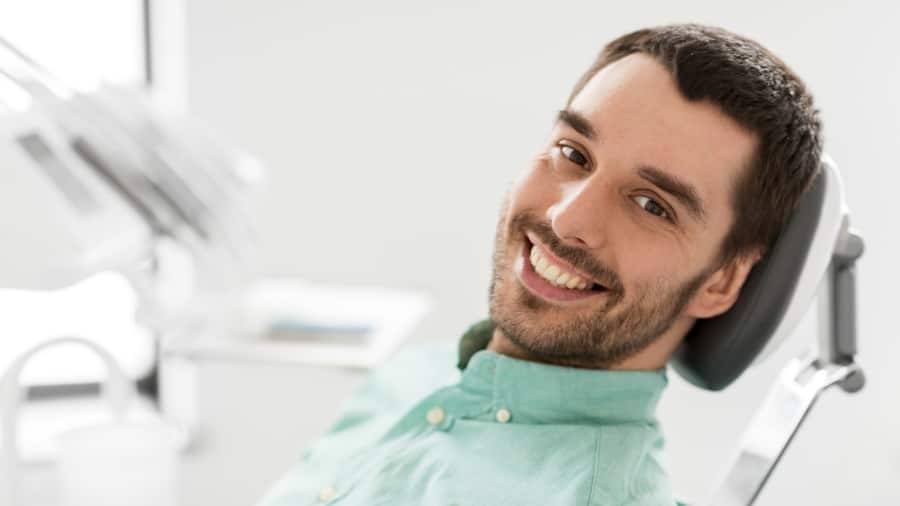Hombre joven con dientes blancos en una silla de ortodoncia