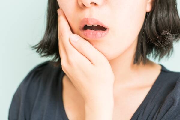 Una mujer con dientes blancos sentada en un auto usando su celular